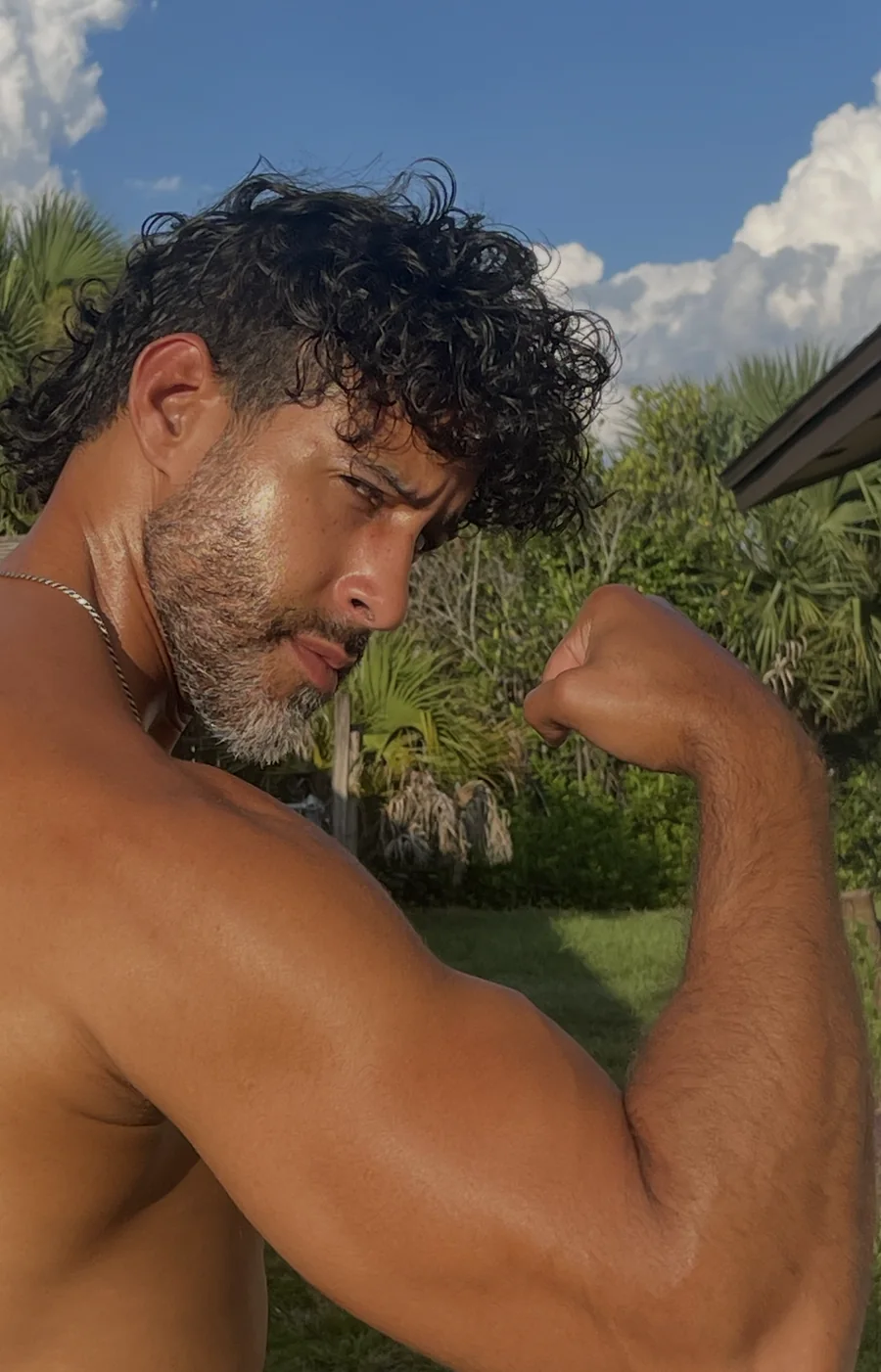 Will Frometa outdoors under a blue sky, flexing his arm and looking toward the camera